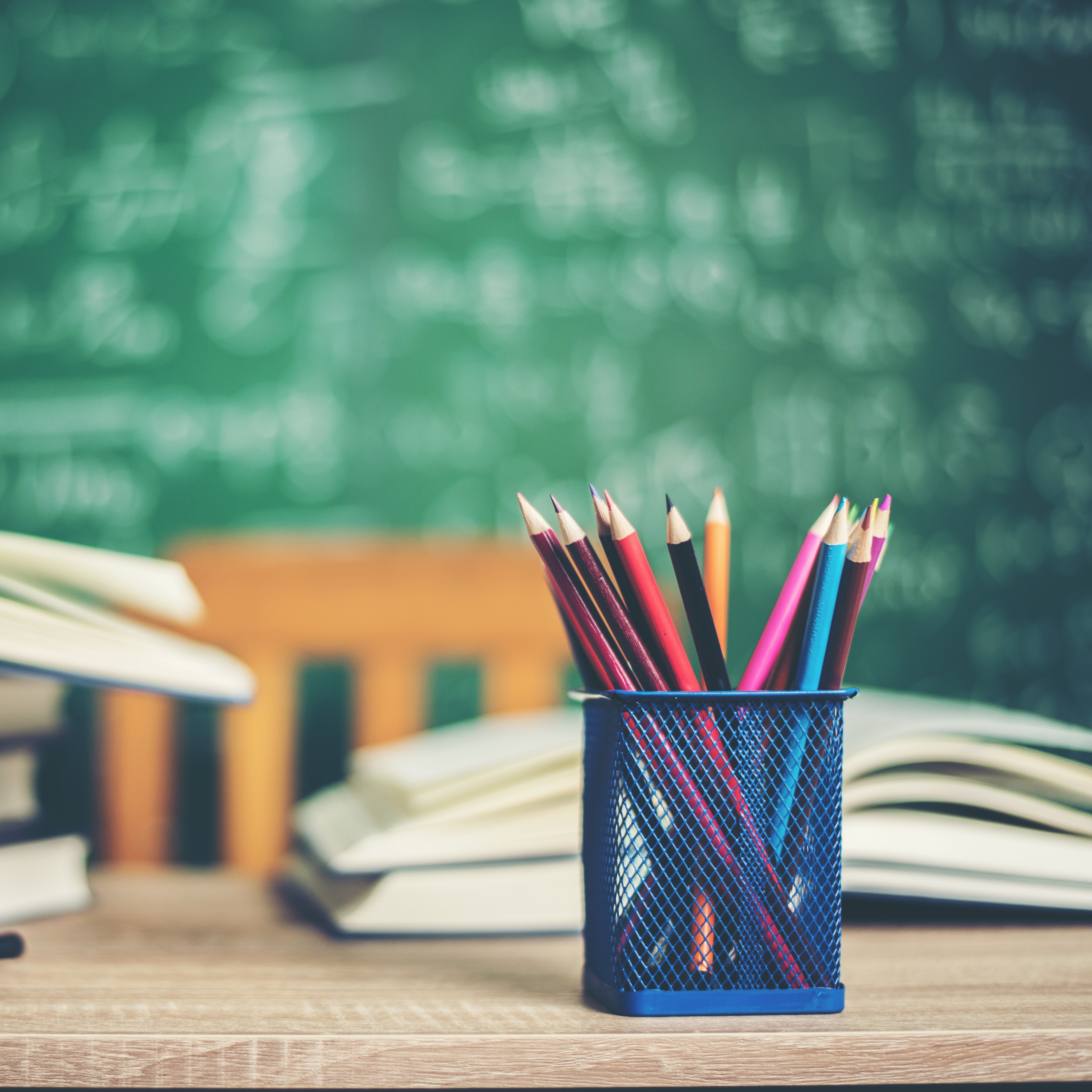Books, globe, and colored pencils on a classroom desk